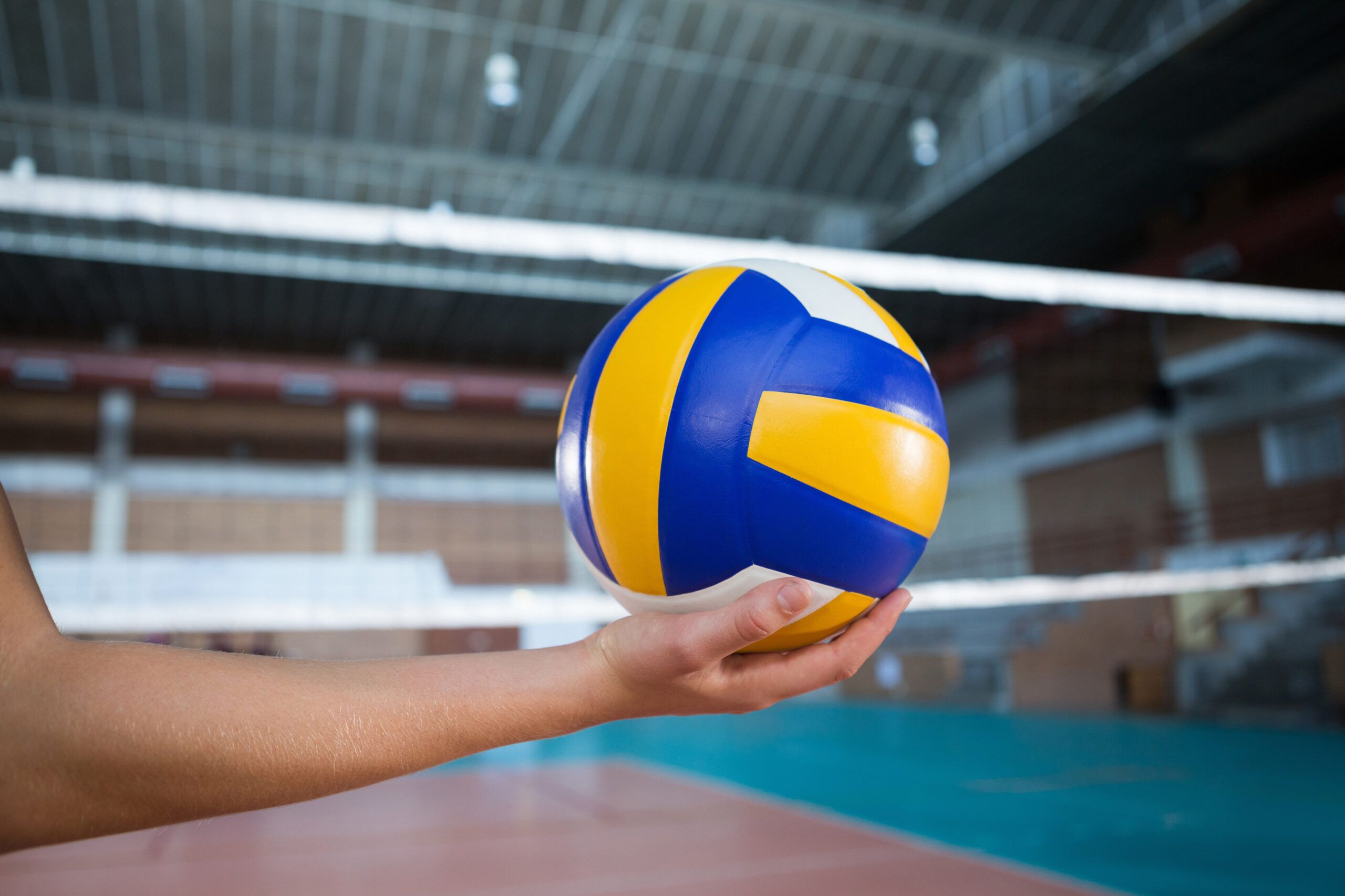 Close-up of female player holding volleyball in the court